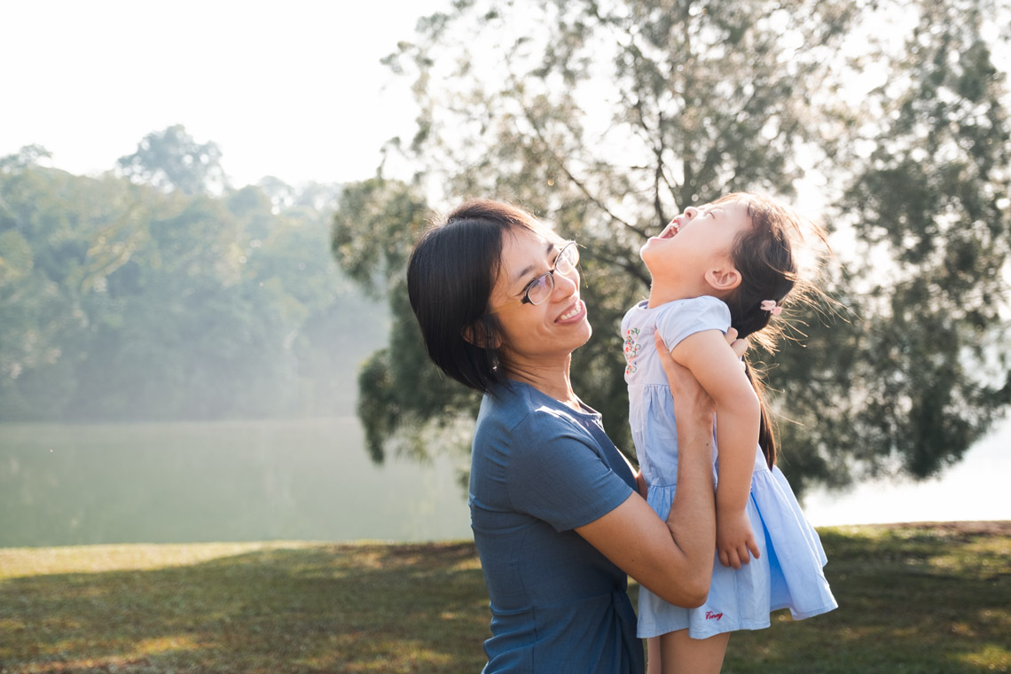 Mom holding his toddler daughter next to a beautiful reservoir