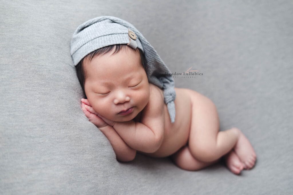 Ultra cute baby doing a side sleeper pose in his newborn photography session