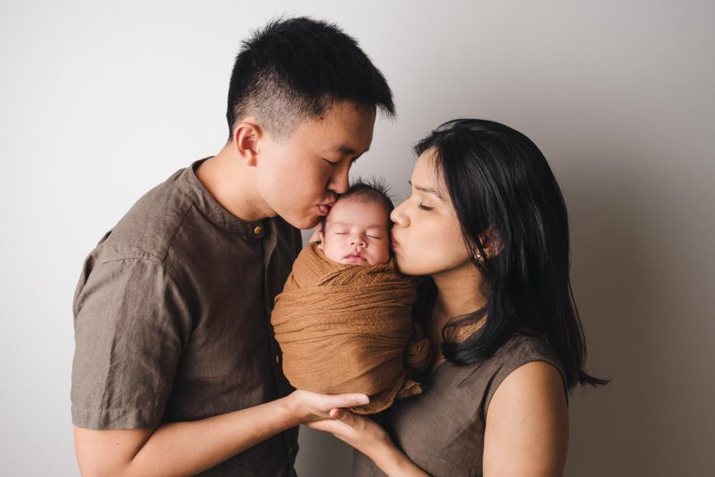 Newborn Photography Parents kissing newborn baby's cheek