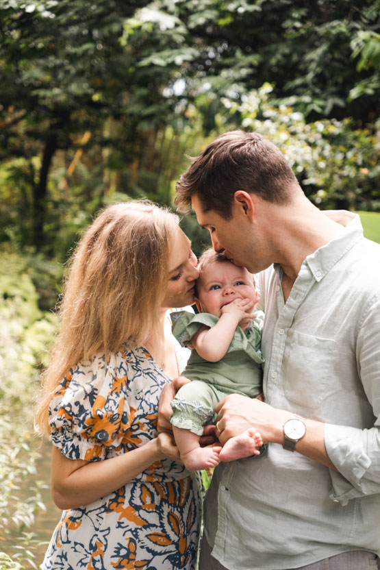 Parents kissing baby in outdoor photoshoot