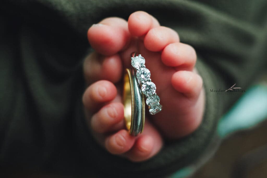 Newborn photography Singapore Closeup shot of parents wedding rings in baby's feet