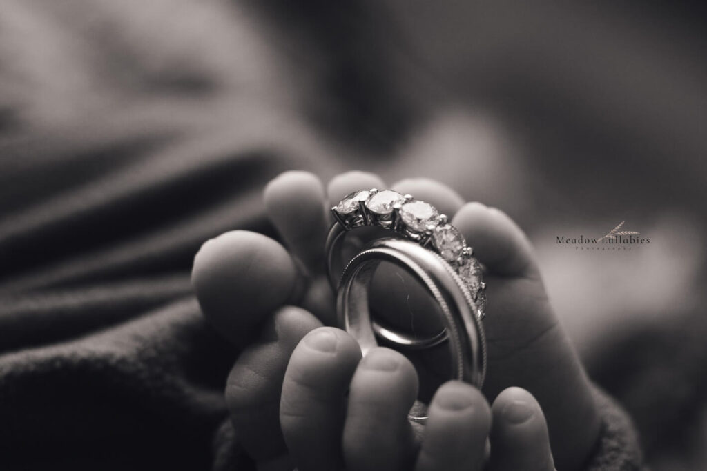 Close-up shot of parents wedding rings in newborn baby's feet