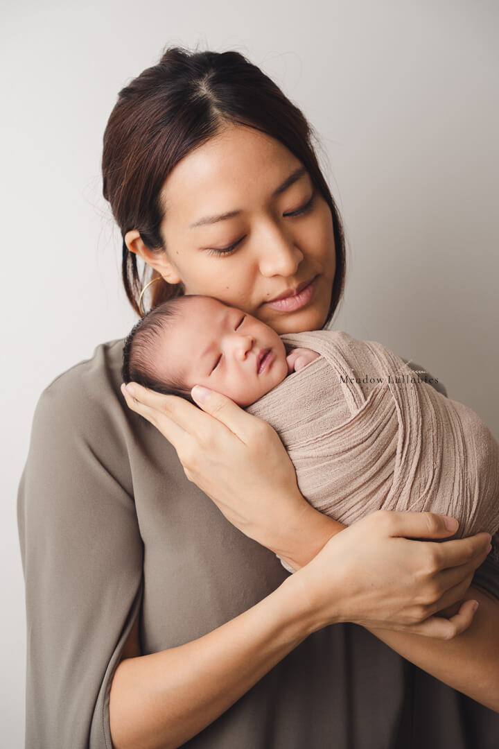 Mother cradling and posing with her newborn baby boy during photoshoot