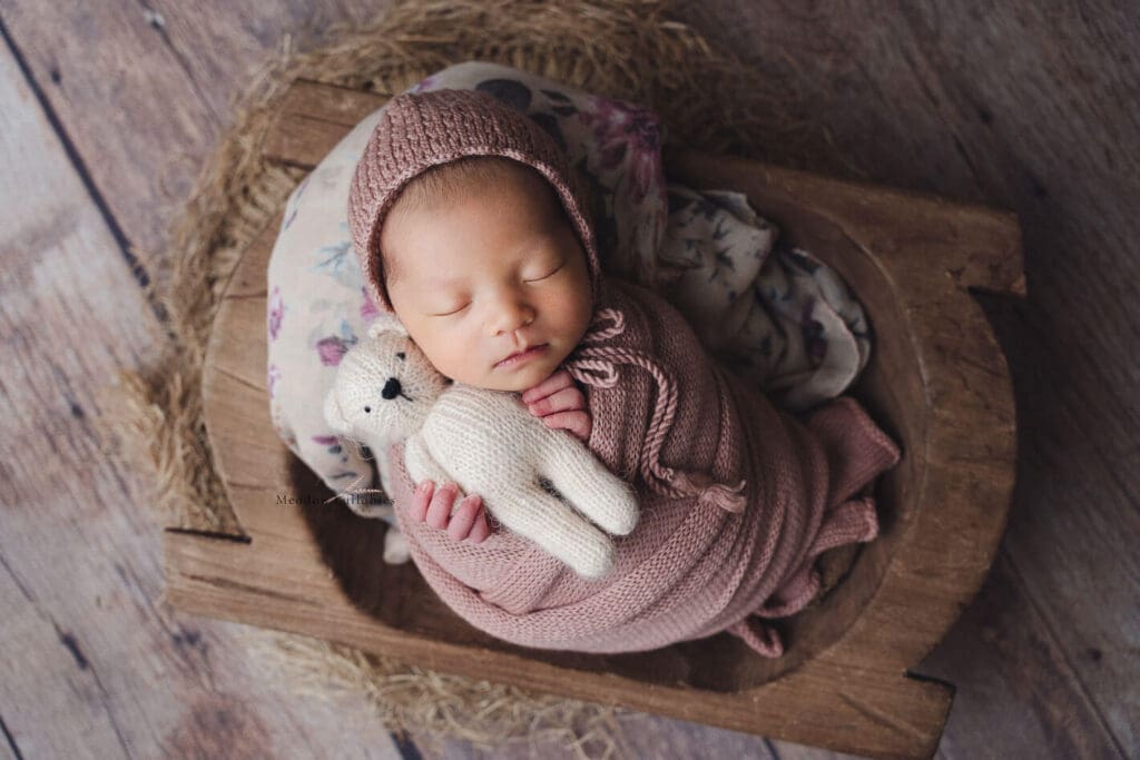Newborn photography Singapore Baby girl holding soft toy bear in crate prop