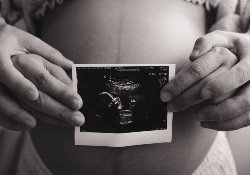 Maternity photoshoot - couple holding ultrasound film in front of tummy