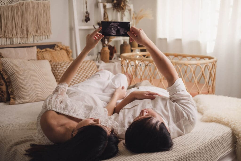 Maternity Photography Singapore Couple laying on bed holding ultrasound scan