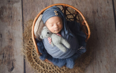 Newborn Photography Singapore Baby Photoshoot, newborn in blue wrap clutching a mini bear soft toy on a vintage stool prop